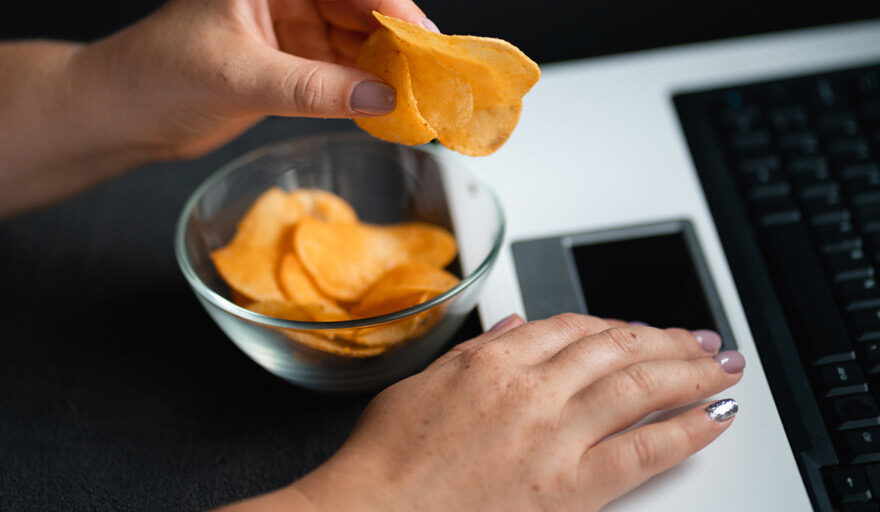 Person eating chips while working on their computer