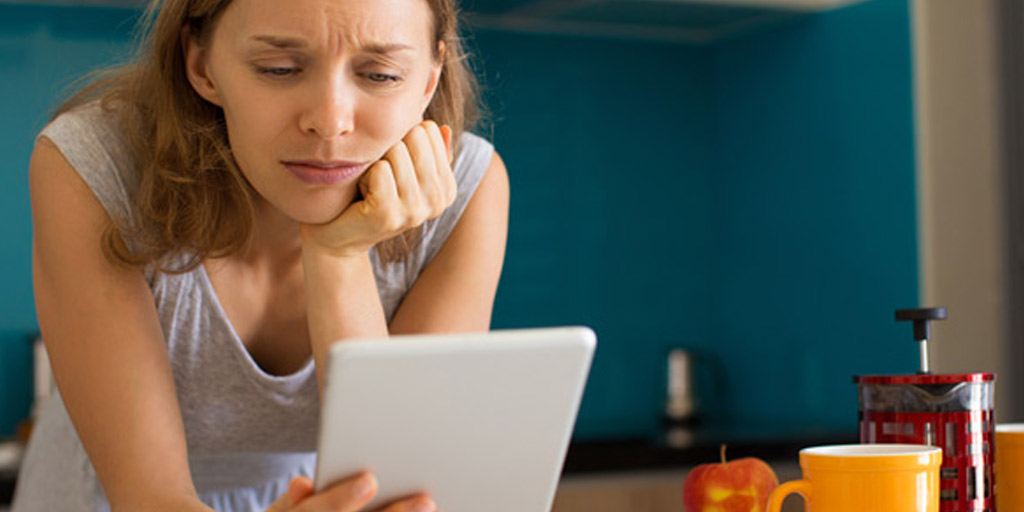 Woman staring at tablet looking disappointed
