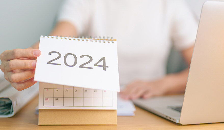 A person sitting at their desk, flipping the calendar to the year 2024.