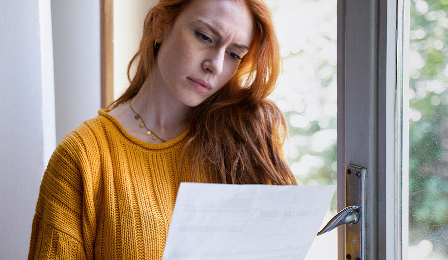 Woman reading a piece of paper and looking confused.