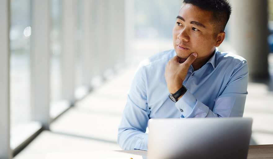 Man sitting at a laptop computer thinking