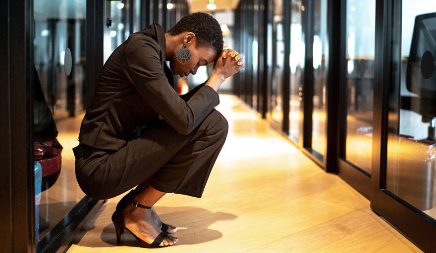 Woman in the hallway at an office kneeling against the wall