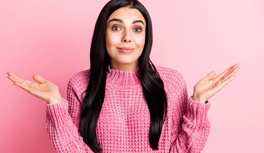 Woman wearing pink with a pink background shrugging